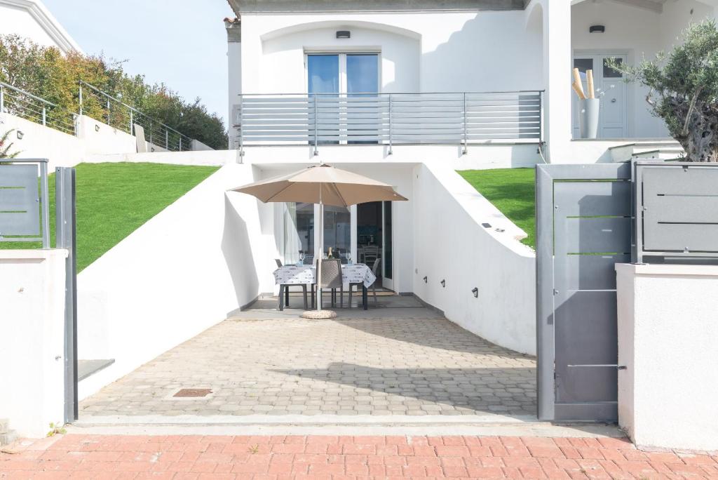 a white house with a table and an umbrella at Bilocale nuovo Budoni centro in Budoni