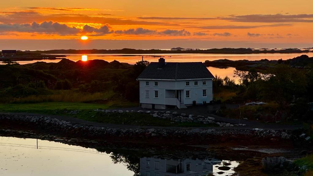a house on an island in the water with the sunset at Langvågen Lodge in Bøstad