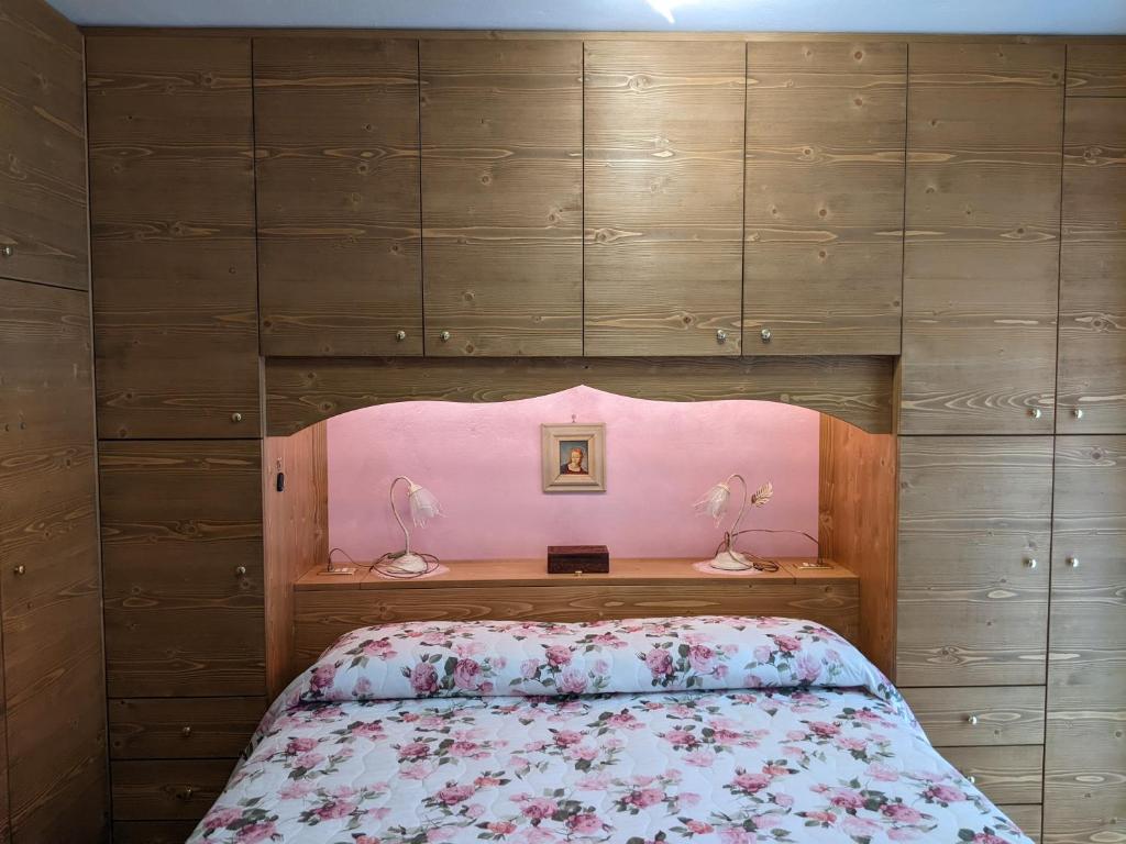 a bedroom with a bed with a pink headboard at Appartamento "Vista Lago" in Auronzo di Cadore
