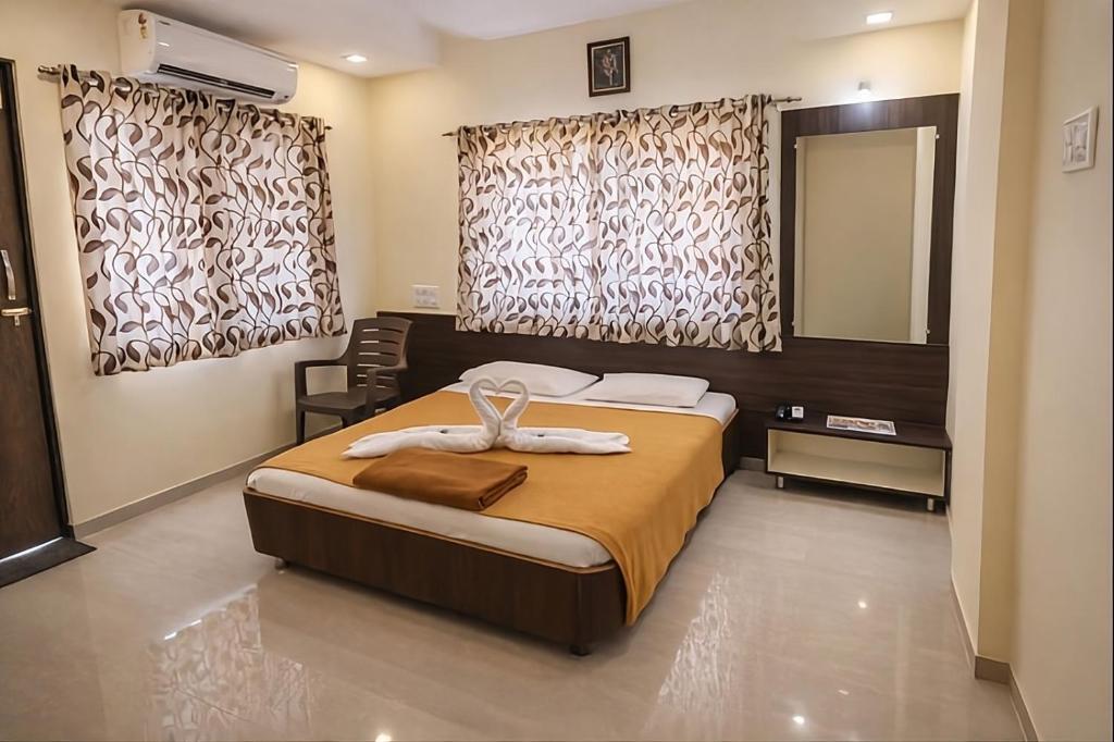 a bedroom with a bed and a mirror and curtains at Hotel Sai Neelam in Shirdi