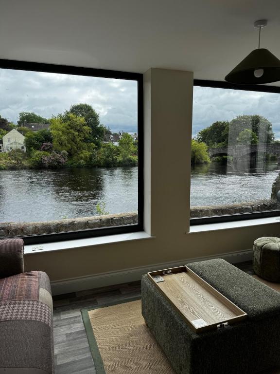 a living room with two large windows looking out at a river at River View Cottage in Newton Stewart