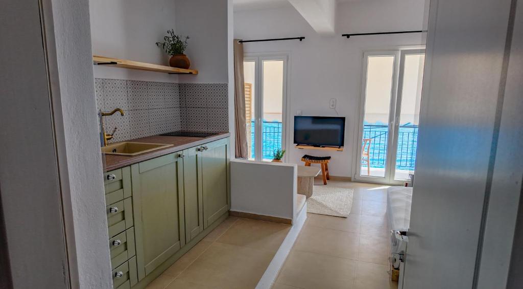 a kitchen with green cabinets and a flat screen tv at To Nisaki in Loutraki