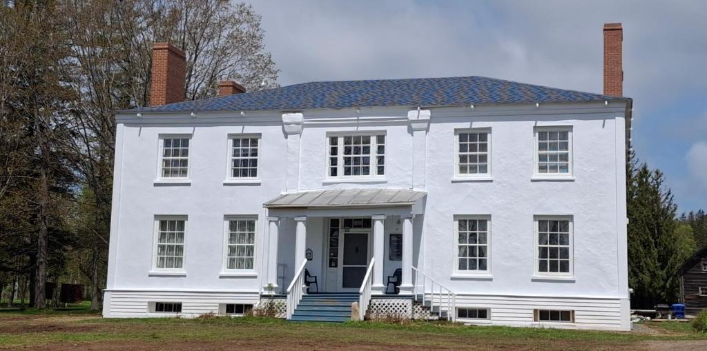 a white house with a front door and stairs at Manoir Hamilton in New Carlisle