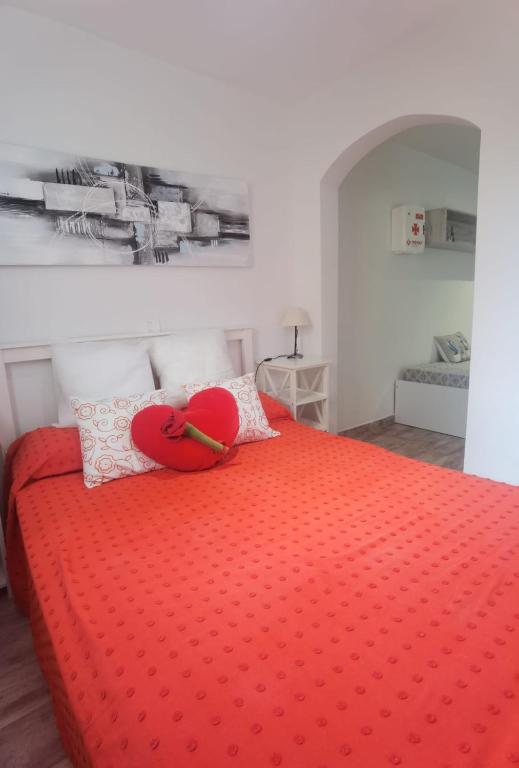 a red bed with a red heart pillow on it at Beachsunset apartamento para estancias temporales in Tacoronte
