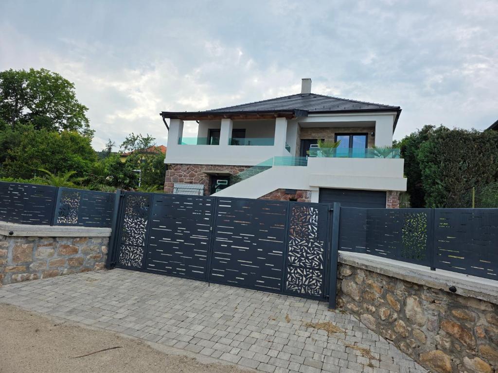 a house with a black gate and a stone wall at Random Villa in Révfülöp