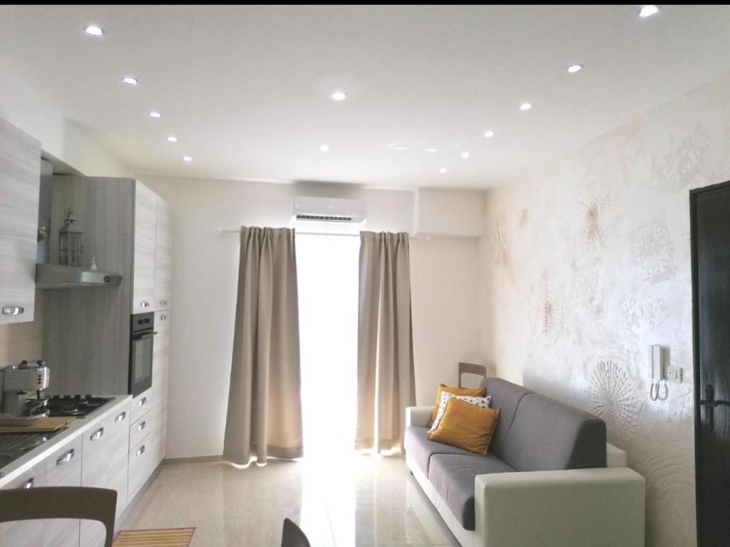 a living room with a couch and a kitchen at Sikelia home in Giardini Naxos