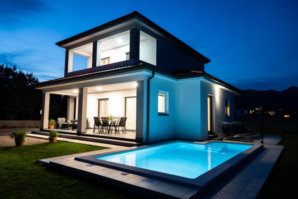 a house with a swimming pool in front of a house at Vila Gaspar in Dražice