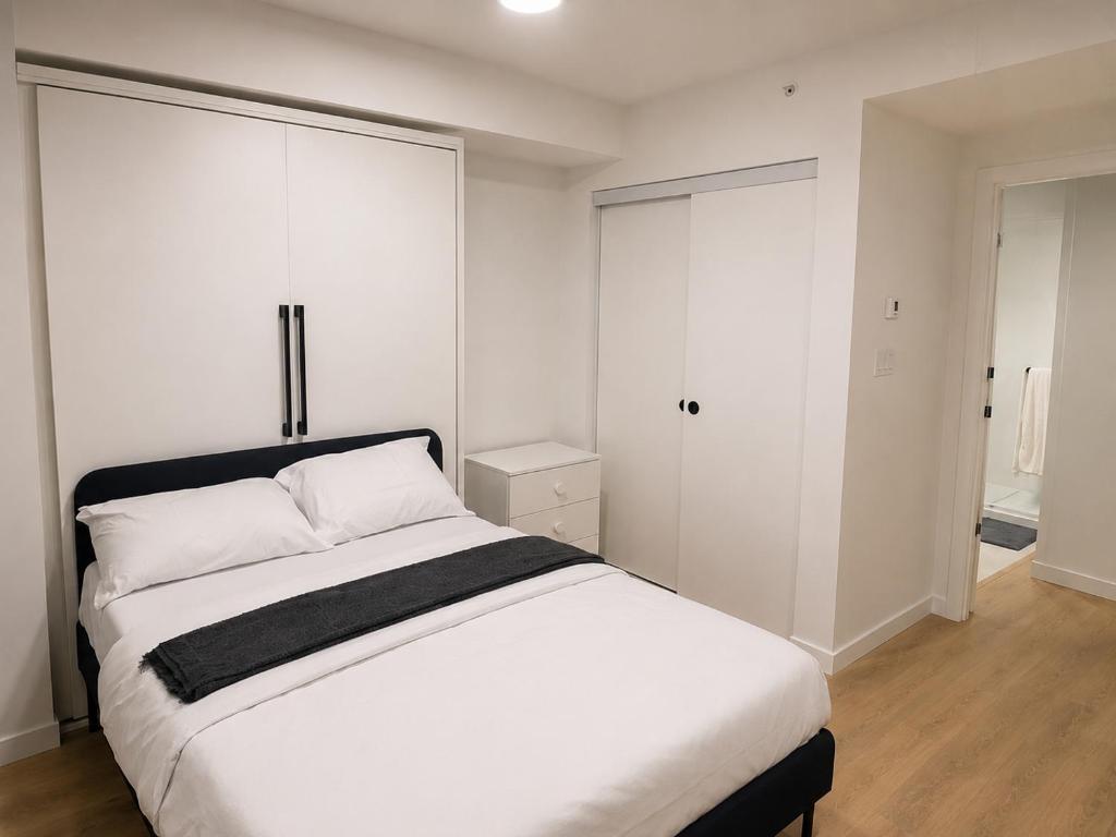 a bedroom with a white bed and white cabinets at Modern suite in Surrey
