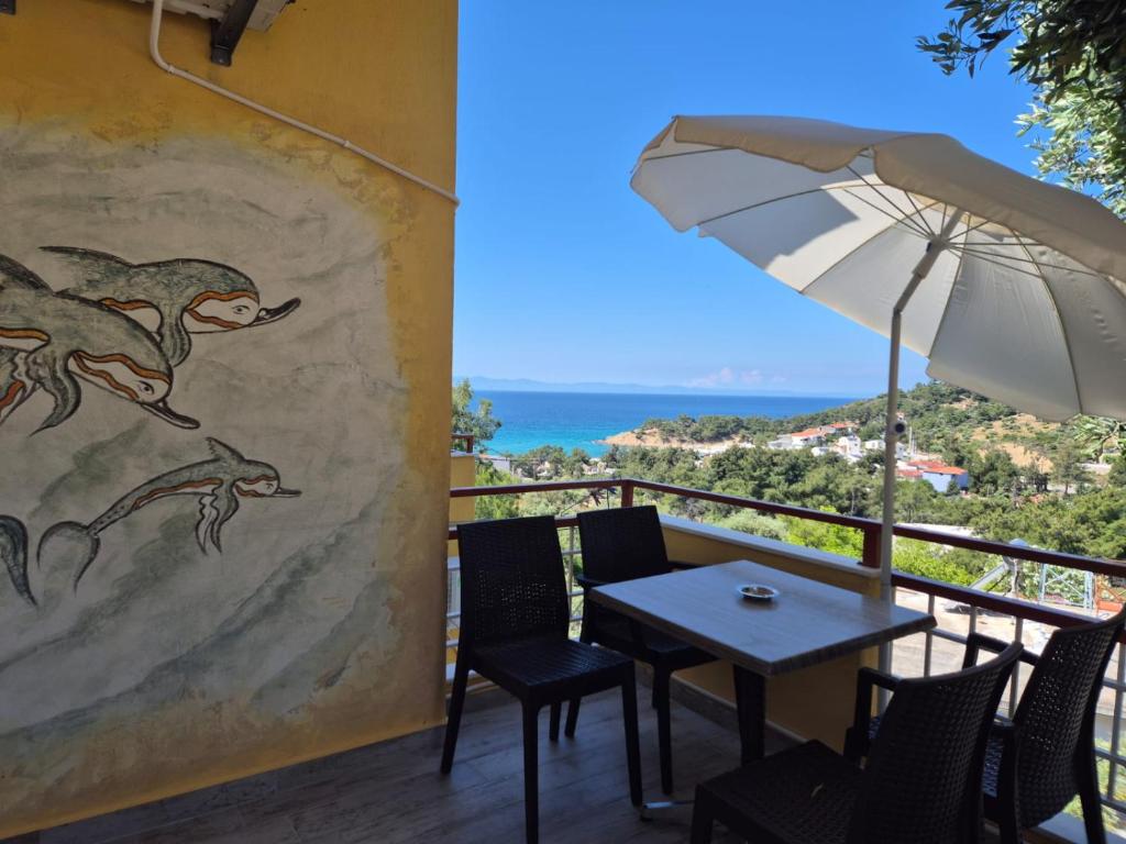 a patio with a table and an umbrella at Sunset Apartments & Studios in Limenaria