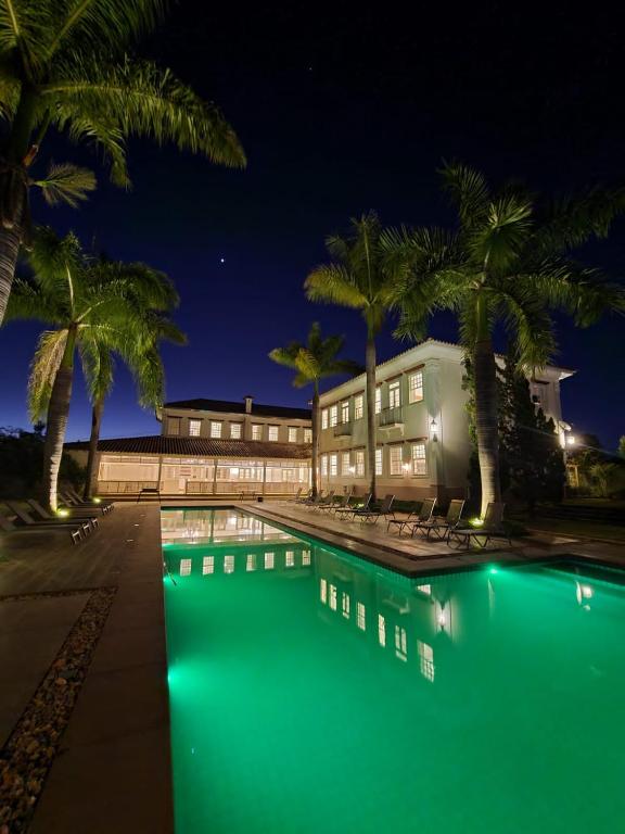 a swimming pool with palm trees in front of a building at Hotel Boutique Inconfidentes in Tiradentes