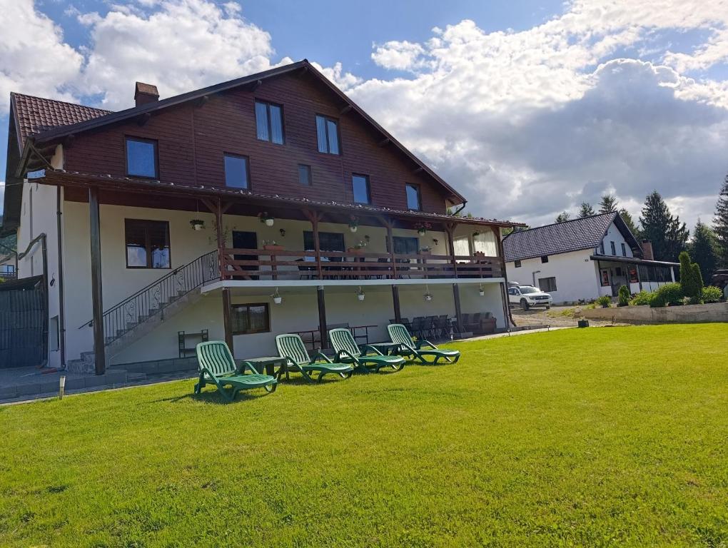 a group of chairs sitting on a lawn in front of a building at Cabana Dany Colibița in Colibiţa