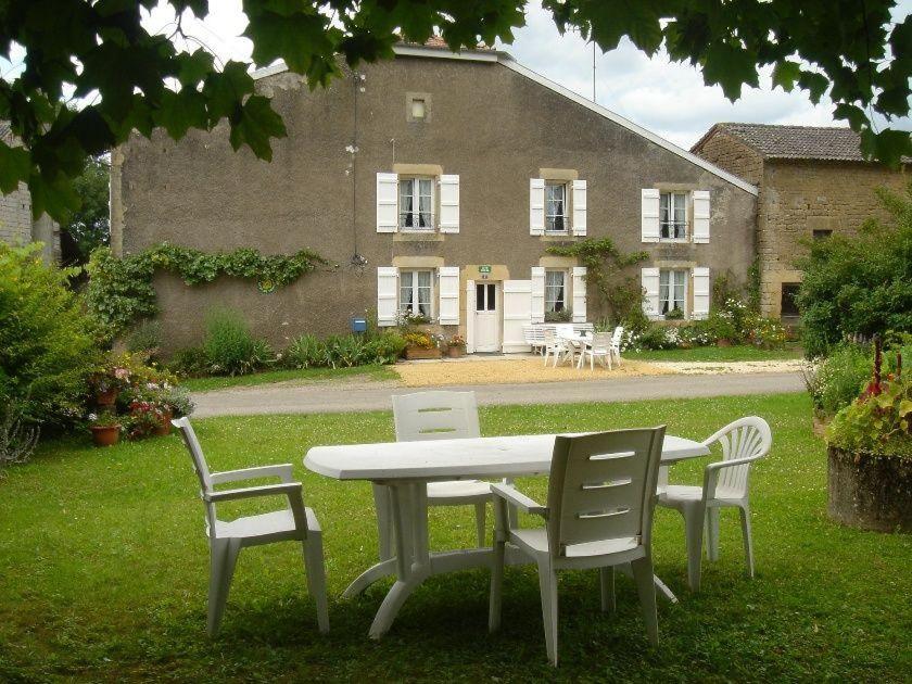 a table and two chairs in front of a building at Gîte de la Buissonniere in Grand-Failly