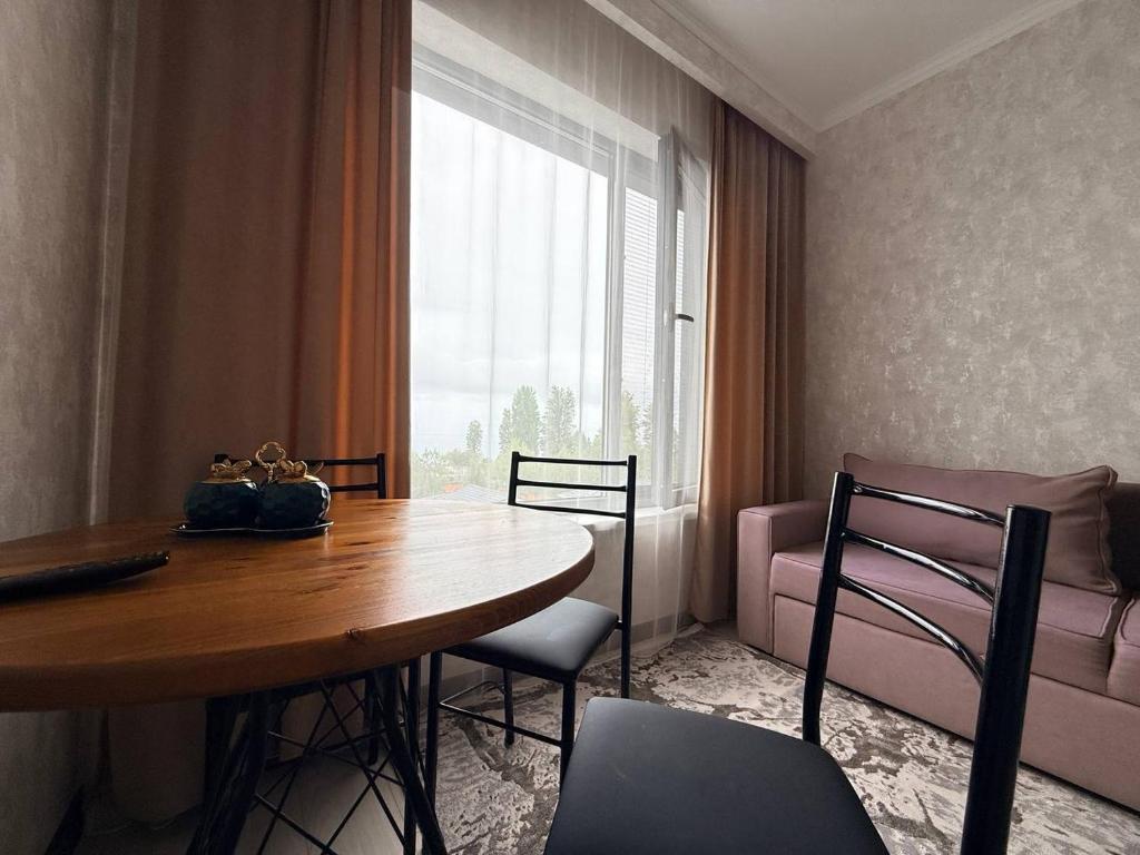 a dining room with a table and chairs and a couch at Novel apartment in Korumdy