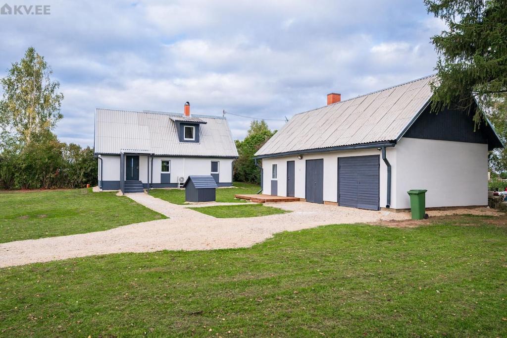 a white house with a garage next to a yard at Voika majutus in Voika