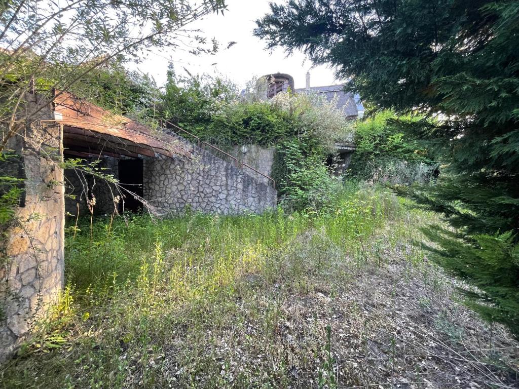 an old stone building with vegetation on the side of a field at Eötvös Hotel in Ajka