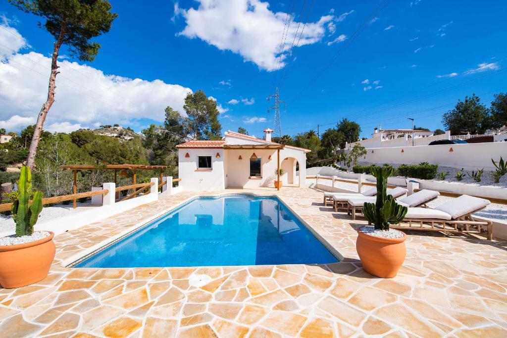 a swimming pool in a patio with chairs and a house at Villa Mawaki Calpe in Calpe