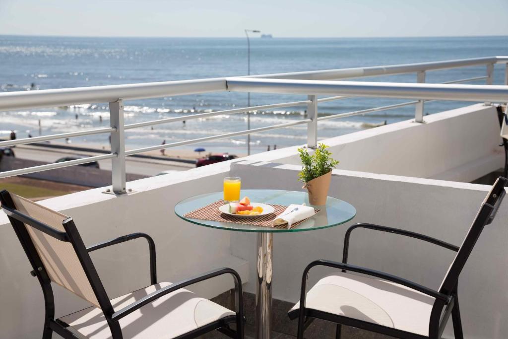 Una mesa y sillas en un balcón con vista a la playa. en Seaview Hotel Boutique, en Punta del Este