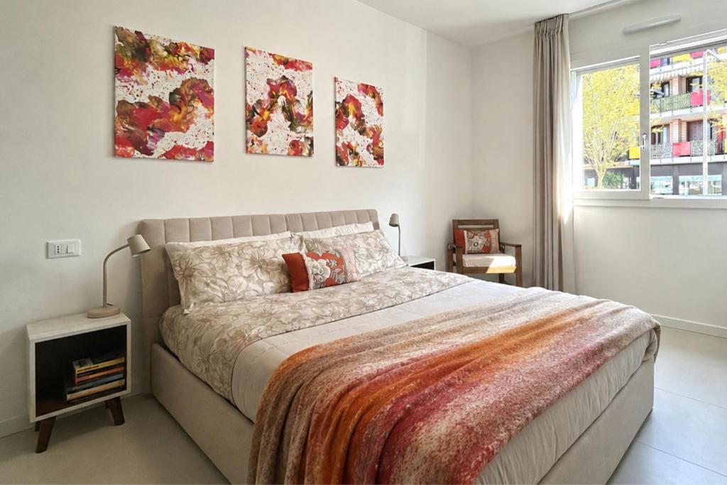 a bedroom with a bed and three paintings on the wall at Malpensa Airport Apartment - 9 min to MXP - Free Parking in Somma Lombardo