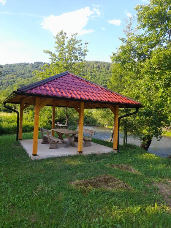 a wooden gazebo with a picnic table in the grass at Apartman Džanan in Jajce