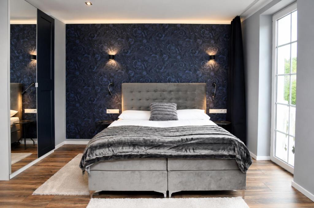 a bedroom with a bed and a blue wall at Hotel Kornblume in Haundorf