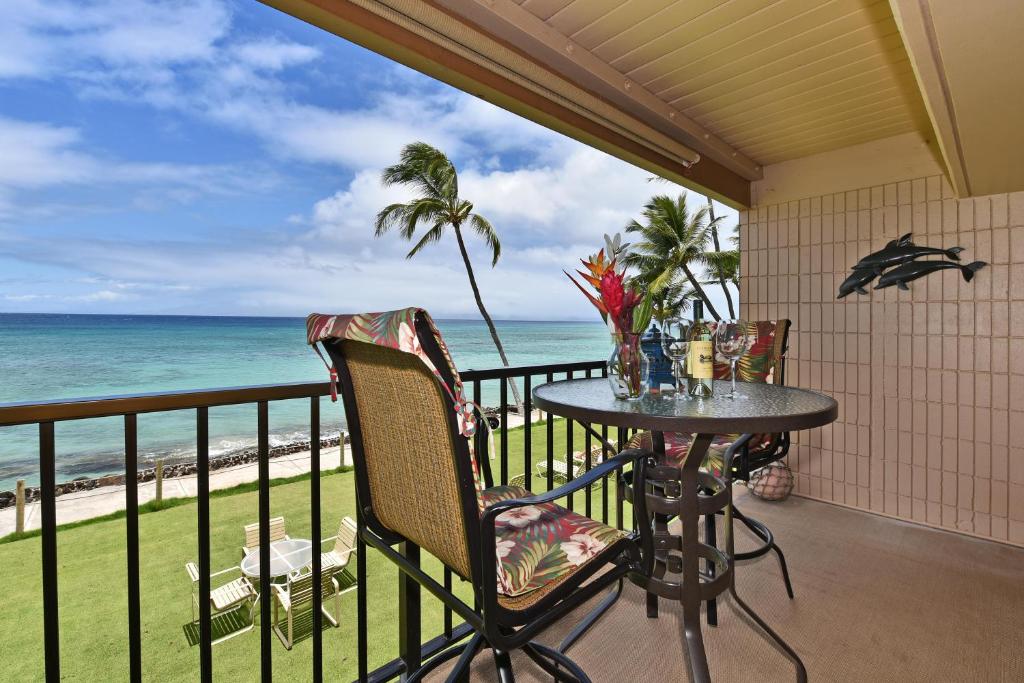 a balcony with a table and chairs and the ocean at Kaleialoha 211 · KA 211 OceanFront 1BD Whale Watch Relax Getaway in Kahana