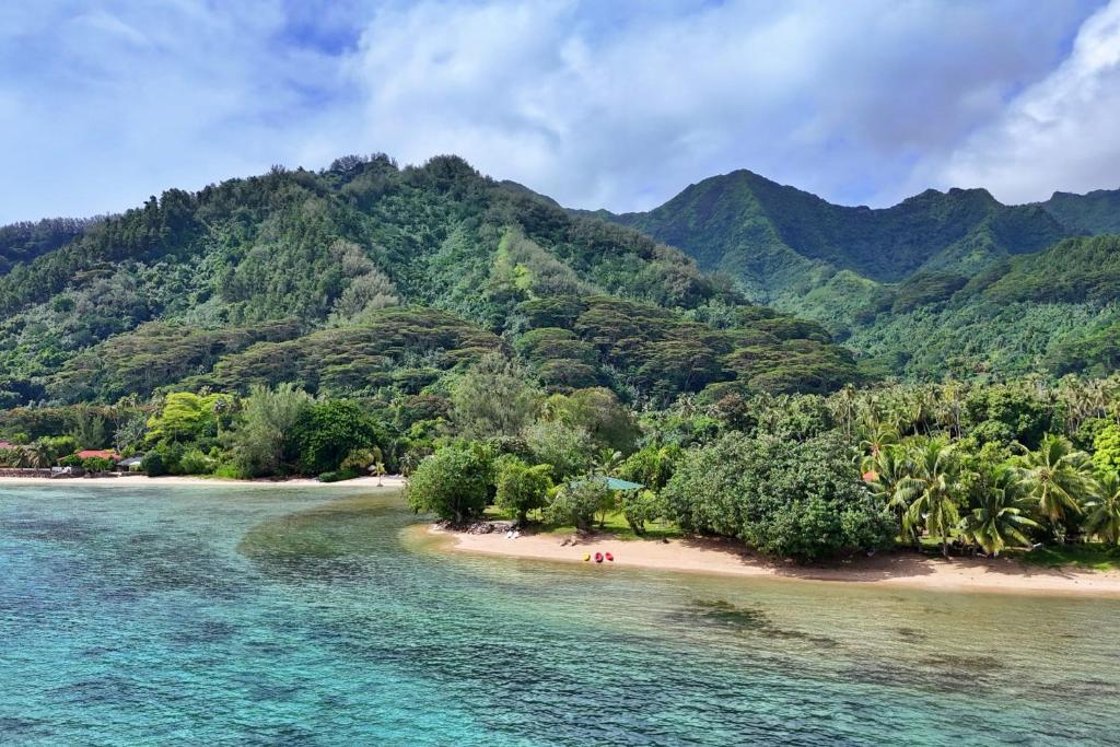 an island in the ocean with people on the beach at Fare Heimery - Private Lagoon Beach in Haapiti