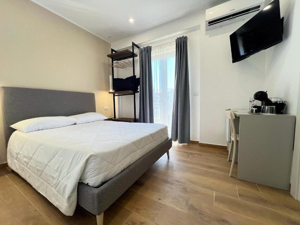 a bedroom with a bed and a flat screen tv at Kalispera Rooms in Scalea