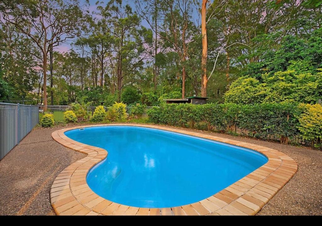 a swimming pool with a brick path around it at Pool house in Marsden