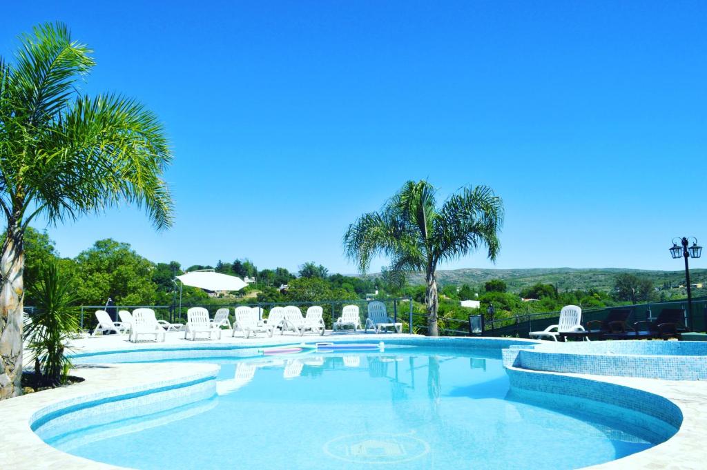 a swimming pool with chairs and palm trees at Solares de Tanti in Tanti Nuevo
