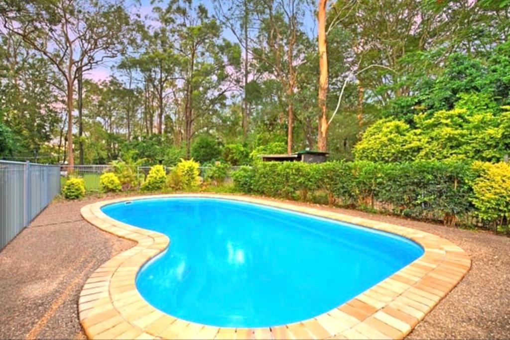 a swimming pool with a brick walkway around it at Pool House with 3 BDR 2 AC in Marsden