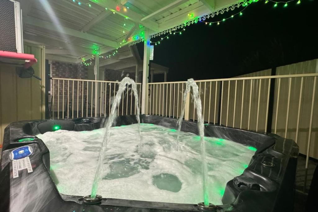 a jacuzzi tub in a backyard with green lights at SPA House 4 BDR 5 beds Master with AC) in Boronia Heights