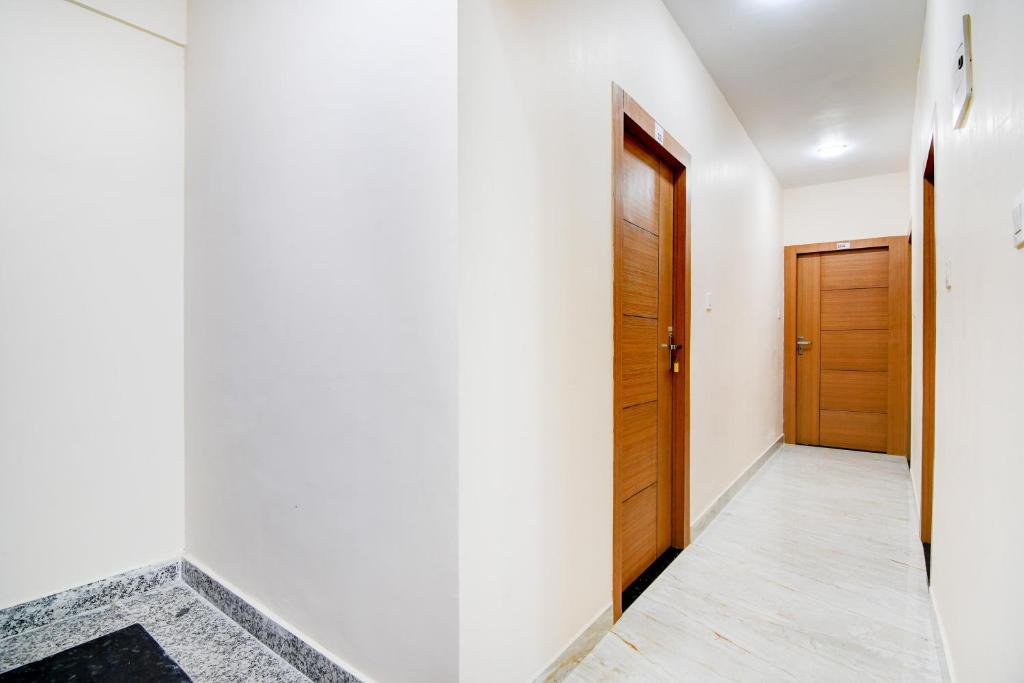 a hallway with white walls and a wooden door at Hotel O by OYO Eco Greenway Retreat in Salua