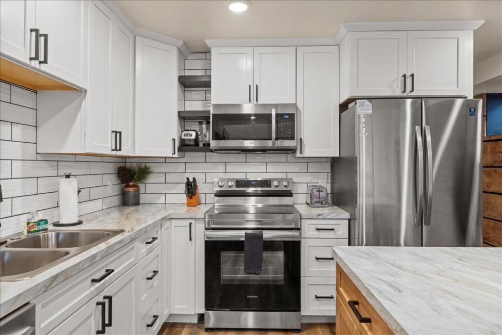 a kitchen with white cabinets and a stainless steel refrigerator at Downtown Hot tub in Red Lodge
