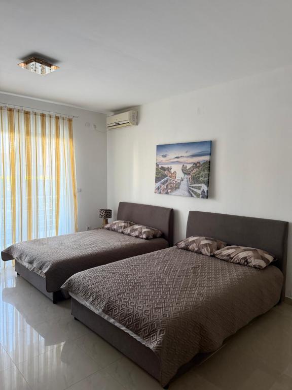 a bedroom with two beds and a painting on the wall at Studio apartman Budex in Đenovići