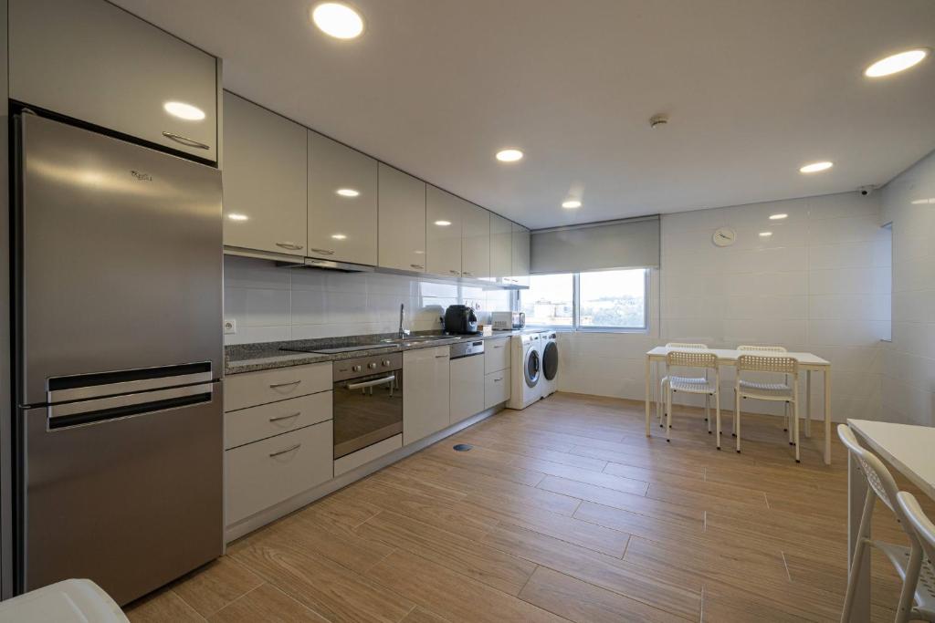 a kitchen with white cabinets and a table and chairs at Central Suítes 3 in São João da Madeira
