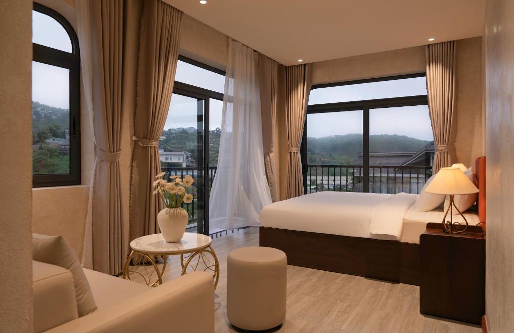 a bedroom with a bed and a couch and windows at Velora Hotel DaLat in Xuan An