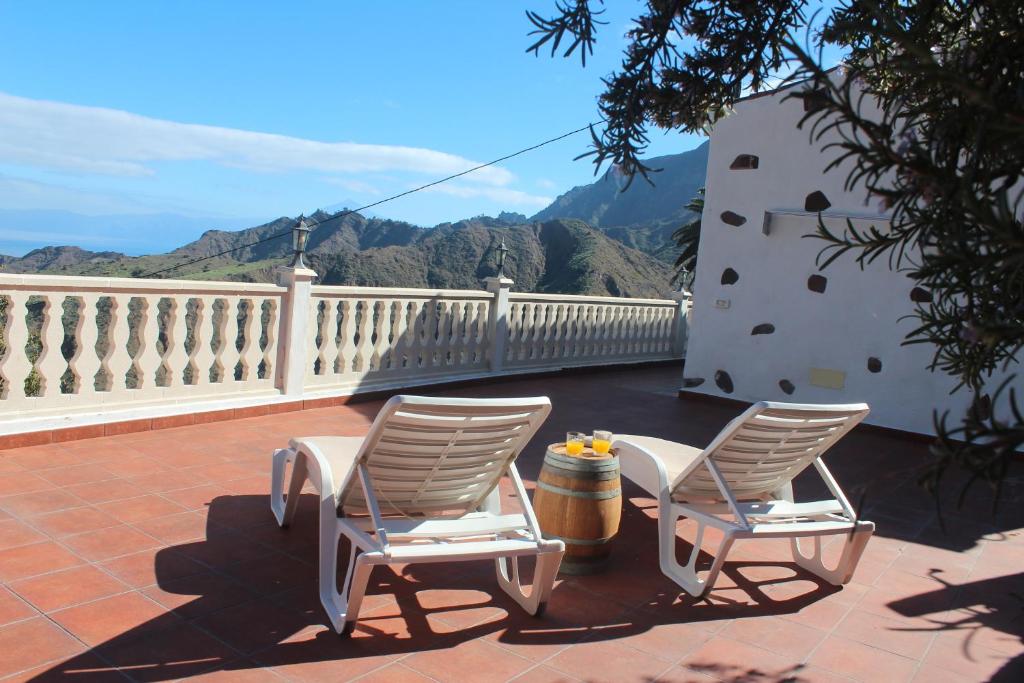 two chairs sitting on a patio with mountains in the background at Casa La Bodega in Hermigua