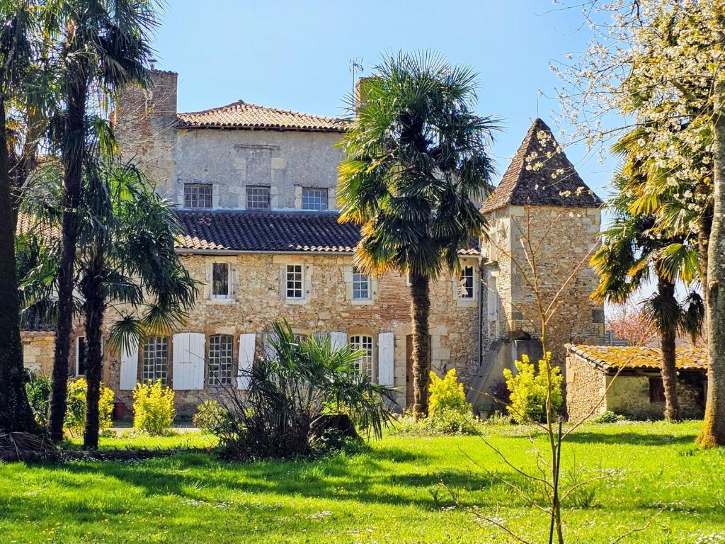 an old stone house with palm trees in the yard at Château Arche d'Aure in Vicq-dʼAuribat