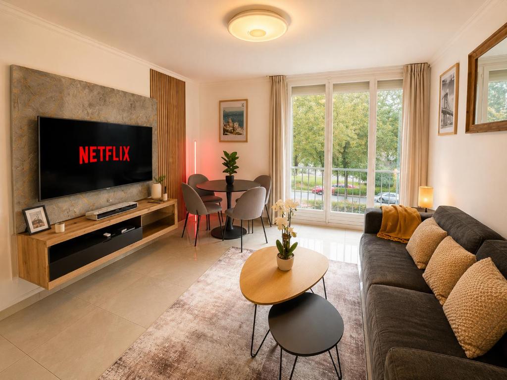 a living room with a couch and a tv at Le cocon du lac in Montargis