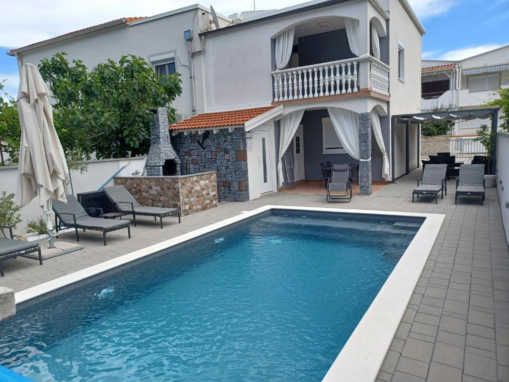 a swimming pool in front of a house at Apartmani Sidro in Privlaka