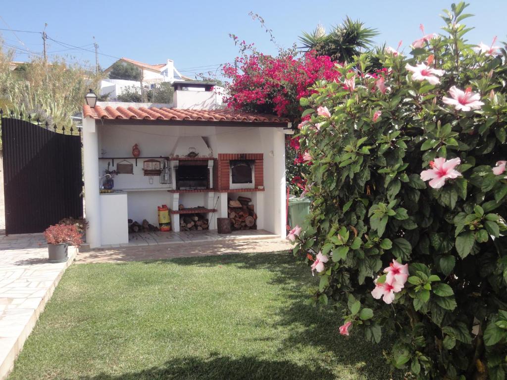 una pequeña casa con flores rosas en el patio en Orchidea Terrace, en Malveira da Serra