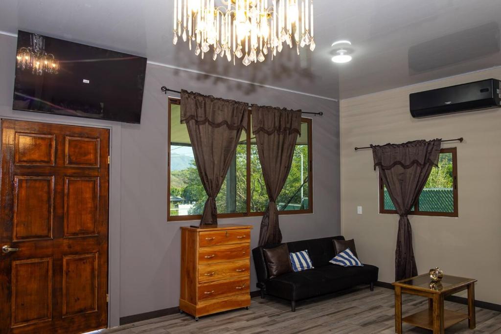 a living room with a couch and a chandelier at Cozy Cabin in Cumbres del Nacimiento, La Unión Sur in Conchagua