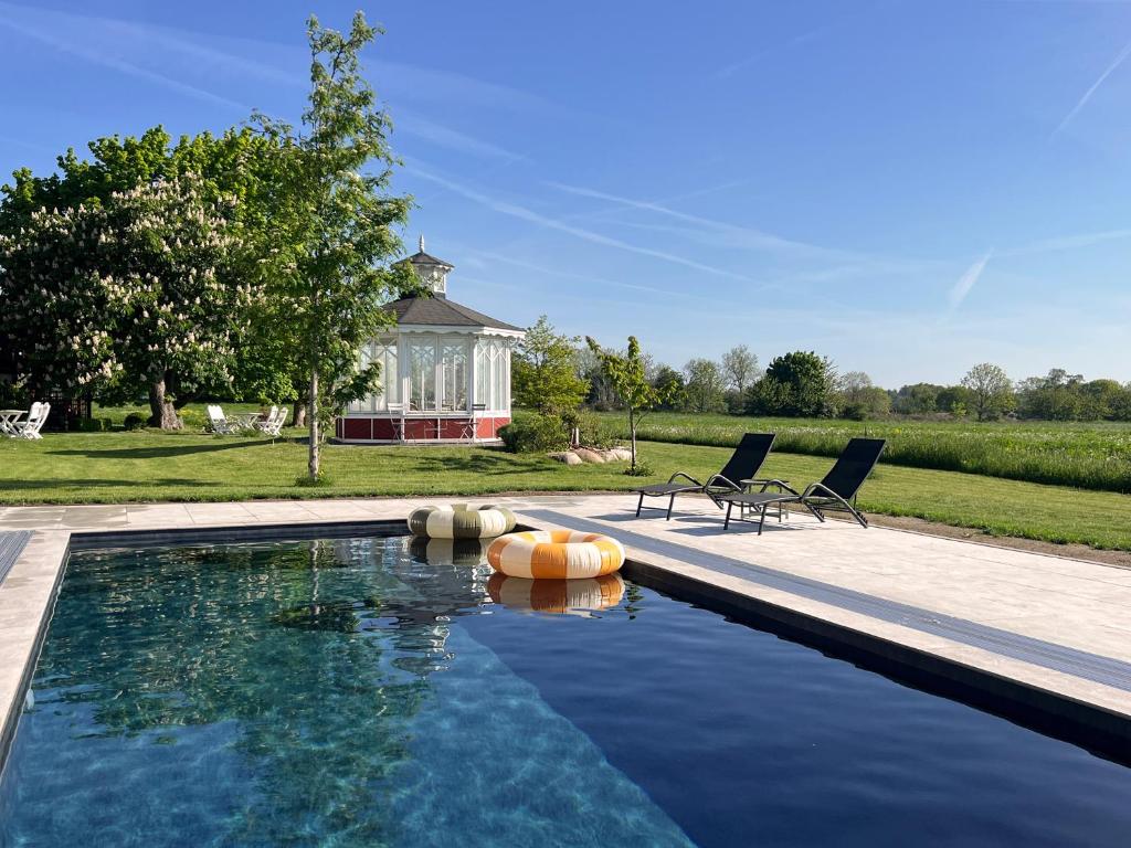 a swimming pool with two chairs next to a house at Torsborgs Gård in Simrishamn