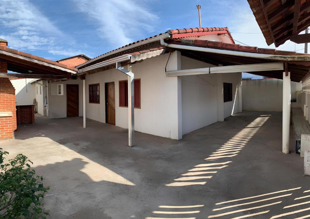 a white building with a parking lot in front of it at Casa temporada Ilha Comprida 350m da praia in Ilha Comprida