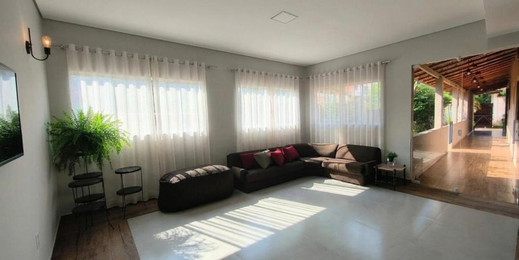 a living room with a couch and some windows at Chácara Umbelina Hospedaria in Cachoeira Paulista