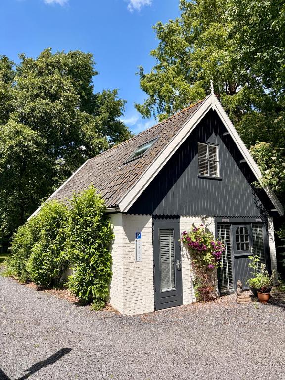 a small white house with a black roof at Goditi La Vita in Hem