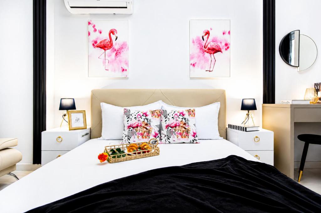 a bedroom with a bed with pink flamingos paintings on the wall at OCCO by the Jacuzzi in Popeşti-Leordeni