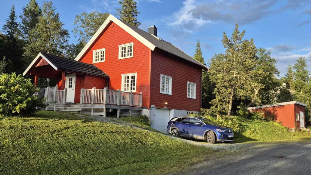 a blue car parked in front of a red house at Kleiva 8 Skorovas in Namsskogan