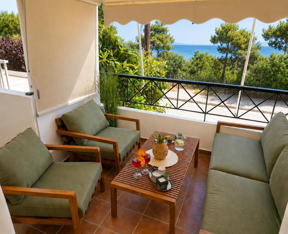 a balcony with chairs and a table and a view of the ocean at Thalassia Pefkias Apartment in Xylokastro