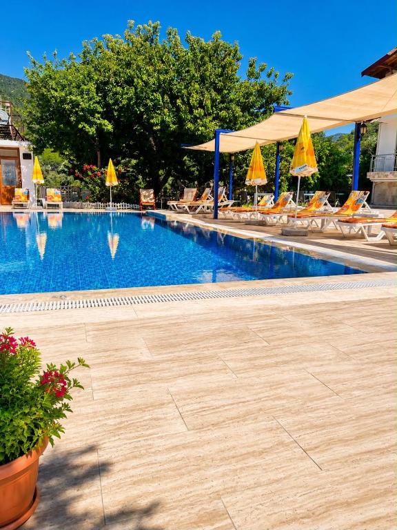 a large swimming pool with chairs and umbrellas at Emir Palas Hotel in Ekincik